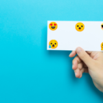 a hand holding index card with emoji faces