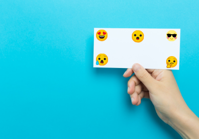 a hand holding index card with emoji faces