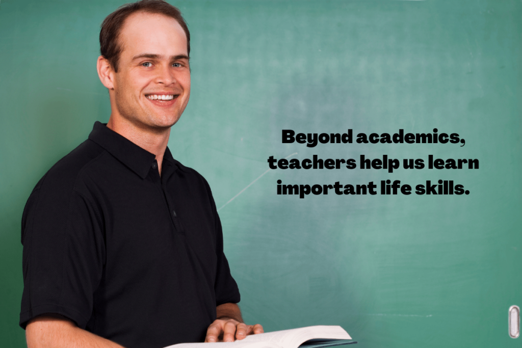 male teacher smiling and holding a book in front of a chalkboard