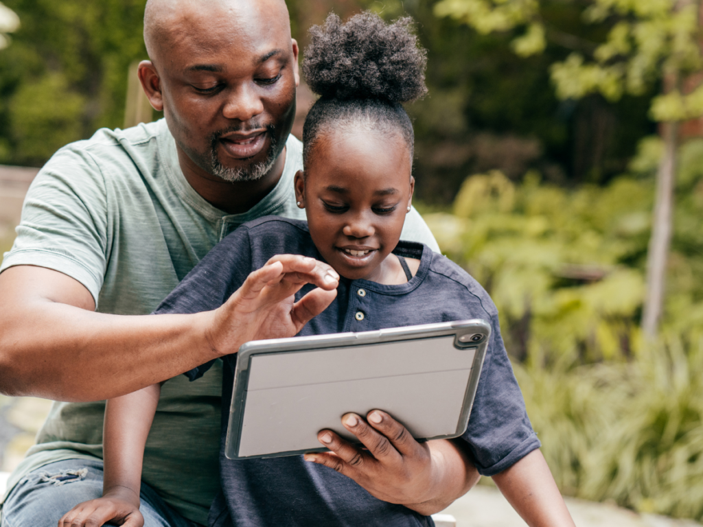 African American father and young daughter working on an electronic tablet