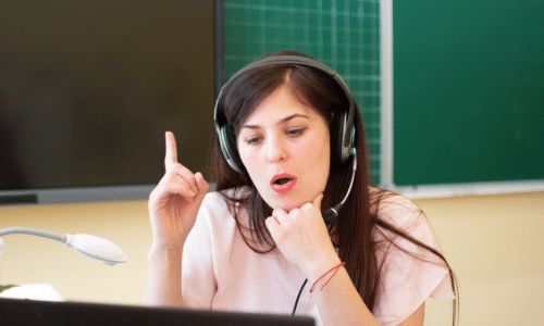 brunette lady wearing a headset with a microphone and interacting with a webinar on her laptop
