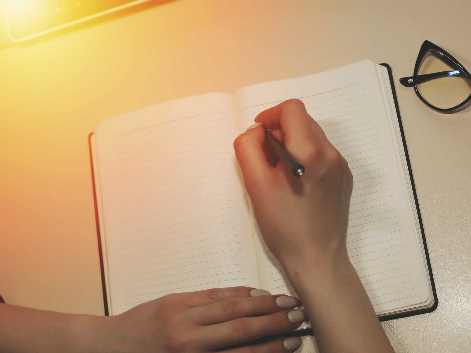 a female's hand writing in a journal with a pen