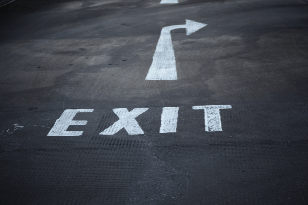 a street with the word EXIT and a right-pointing arrow written in white paint