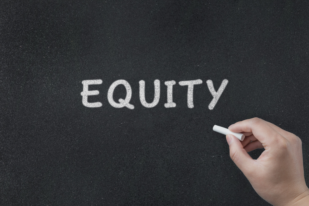 a chalkboard with the word equity being written by a hand with a piece of chalk