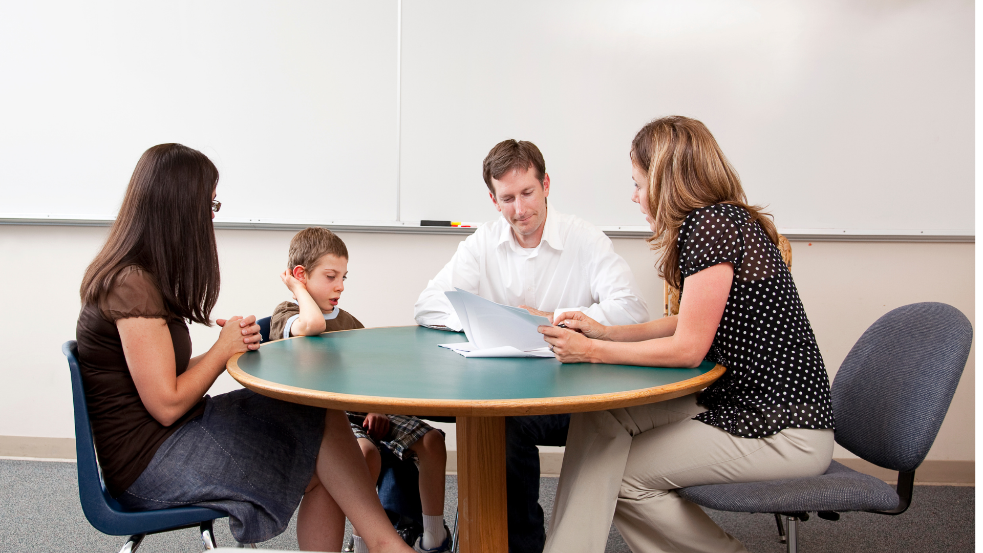 Three adults and a young boy sit at a table for a meeting