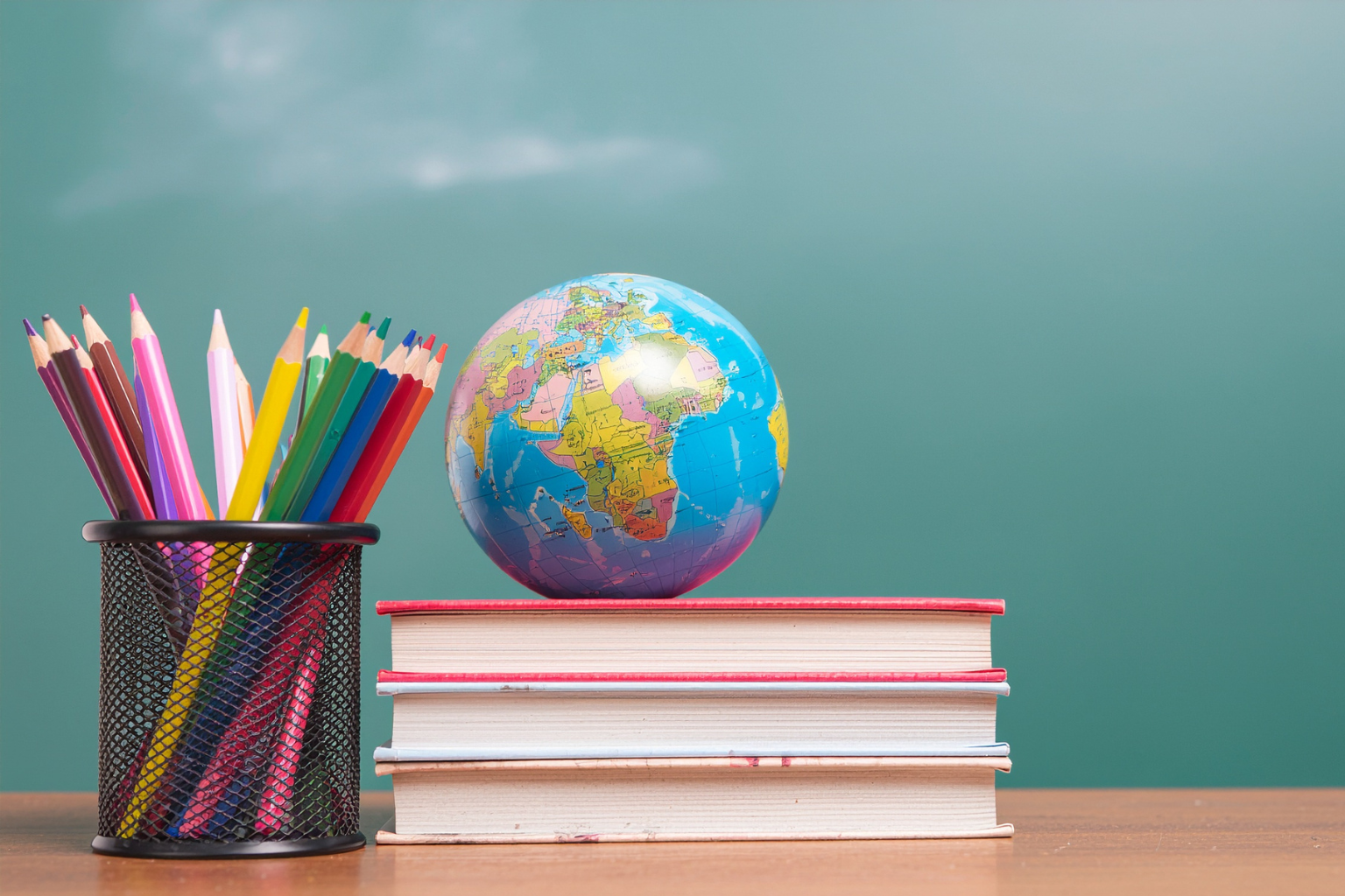 teacher's desk with colored pencils in a cup, globe, and books